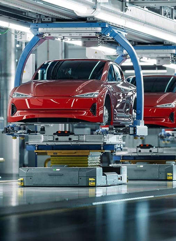 Two red cars on an assembly line.